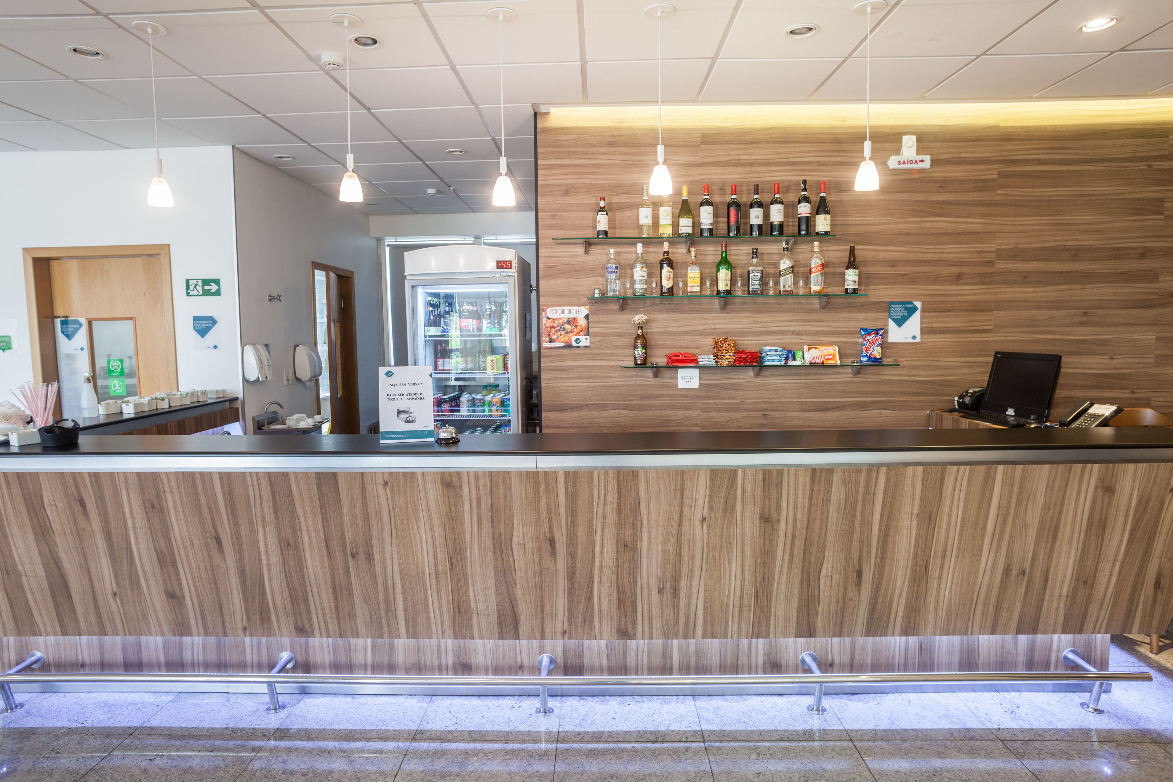 A reception area with a wooden counter, a refrigerator, and a display of bottled beverages.