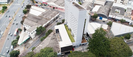 An aerial view of a modern building with a flat roof, surrounded by streets and other buildings.