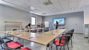 A conference room with a long table, chairs, water bottles, and a presentation screen.