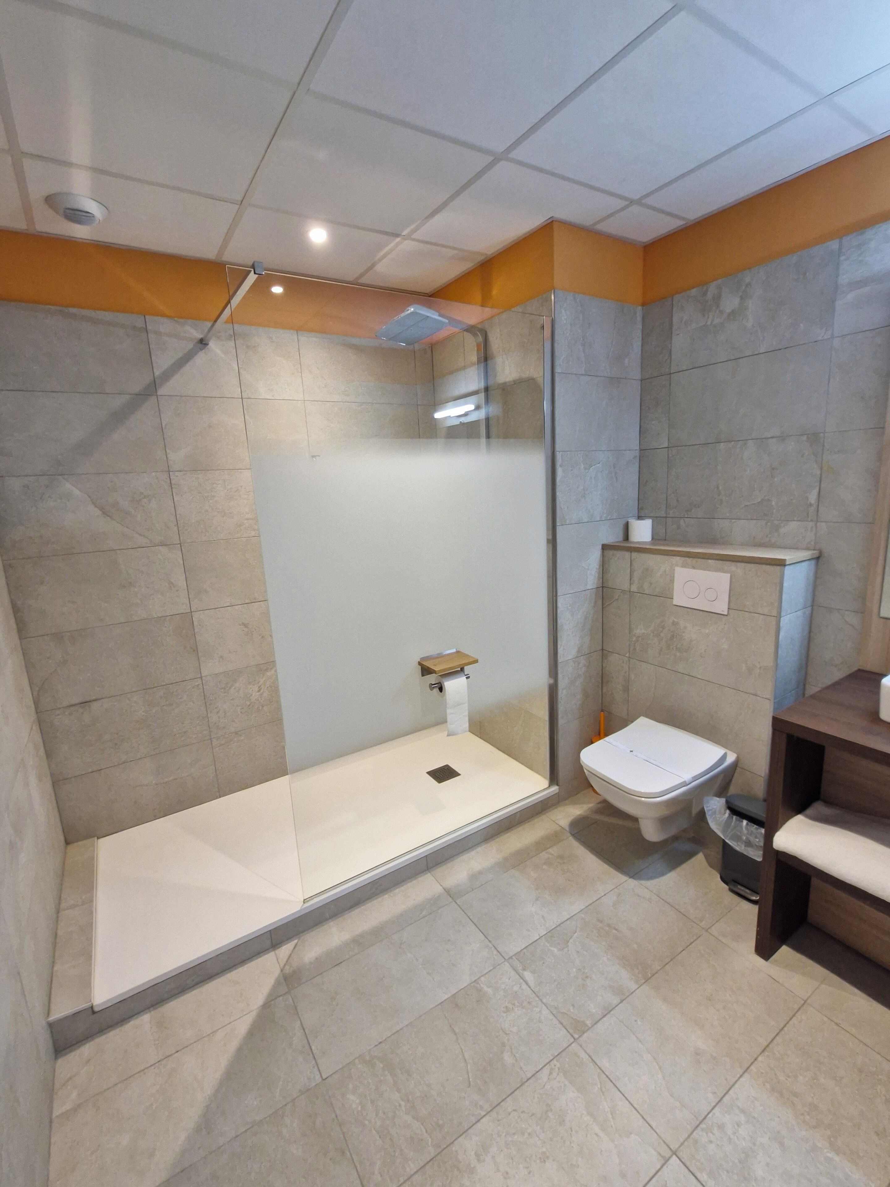 A modern bathroom with a shower, toilet, and sink.
