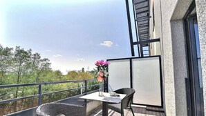 En balkon med fletningsmøbler, et bord og en vase med blomster.