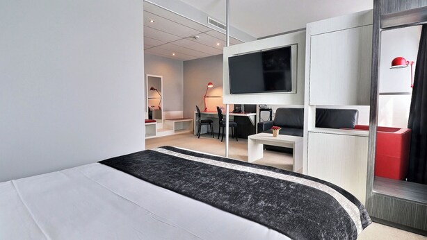 Et moderne hotelværelse med en stor seng, fjernsyn, skrivebord og stol.