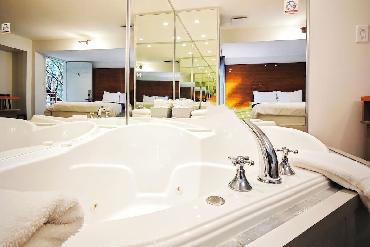 Une salle de bain moderne avec une grande baignoire, un miroir et un meuble-lavabo.
