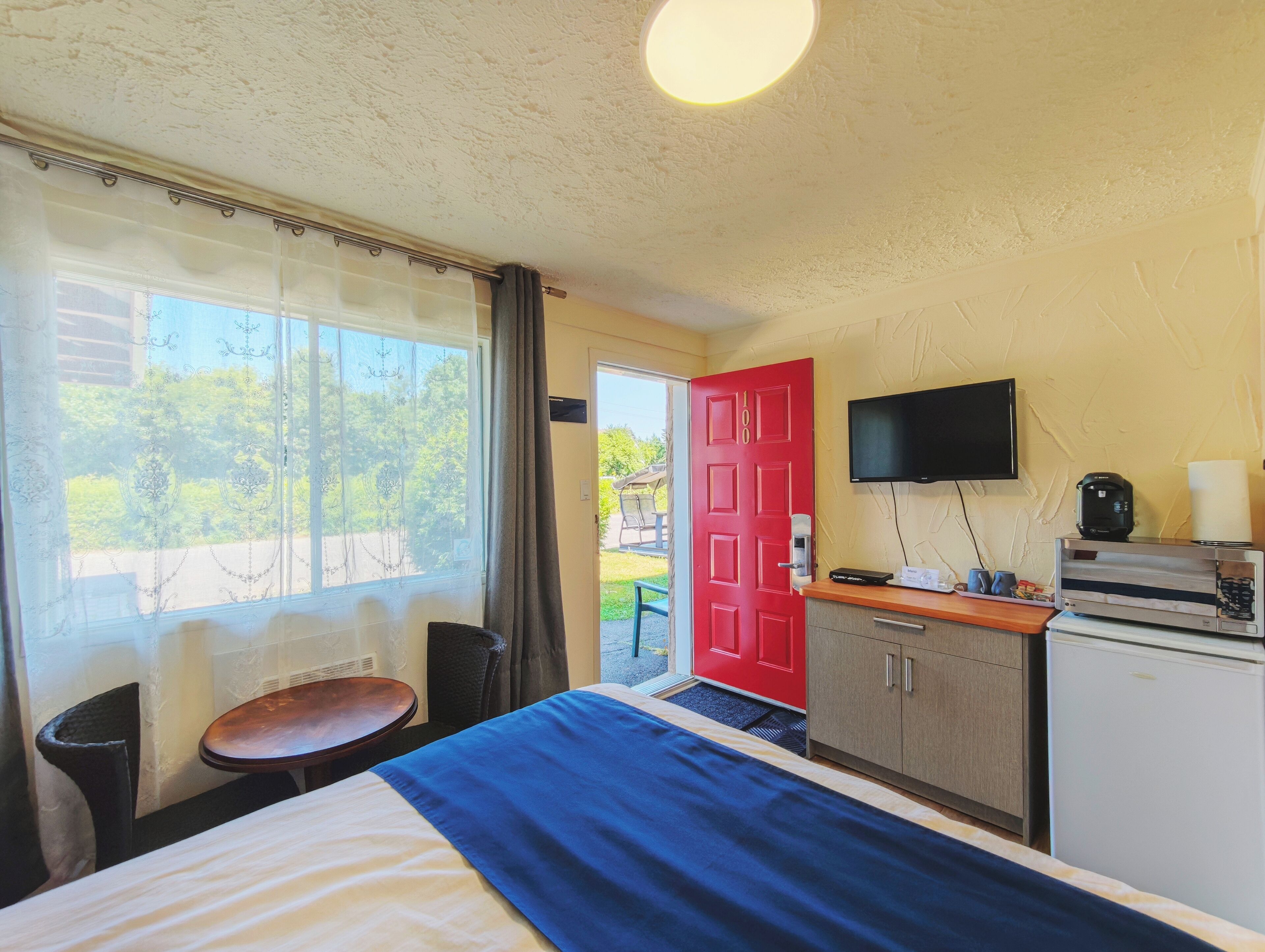 Habitación de hotel con cama, escritorio, televisión y kitchenette.