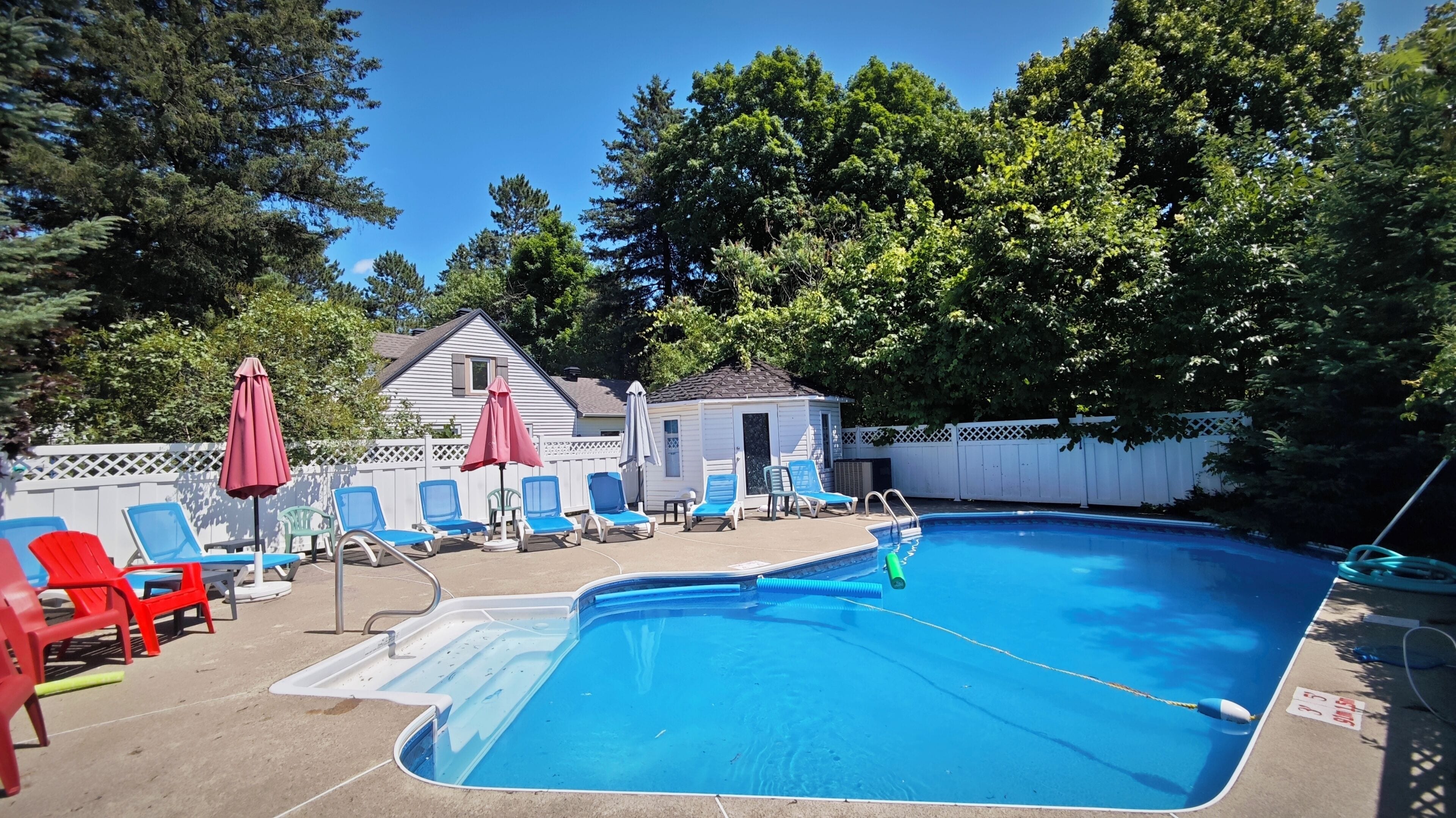 A rectangular swimming pool with a diving board, surrounded by lounge chairs and umbrellas.