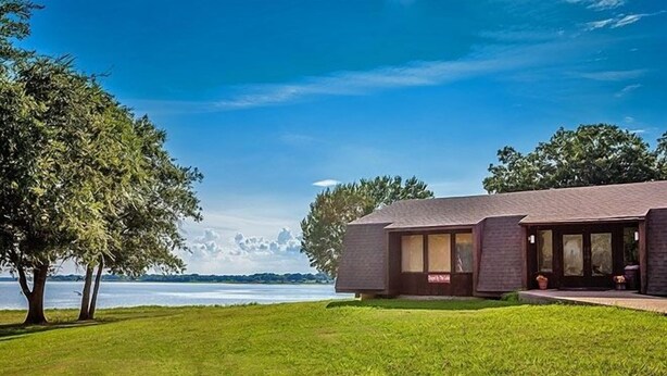 A modern house with a large lawn and a view of the water. - Lake Tawakoni RV Campground (Point)