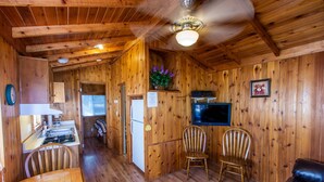 A wooden interior with a dining table, two chairs, a sofa, a television, and a kitchen area. - Lake Tawakoni RV Campground (Point)