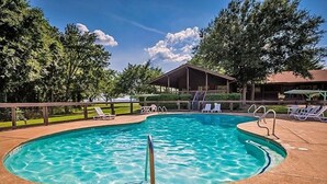 A swimming pool with a wooden deck, lounge chairs, and a covered pavilion. - Lake Tawakoni RV Campground (Point)