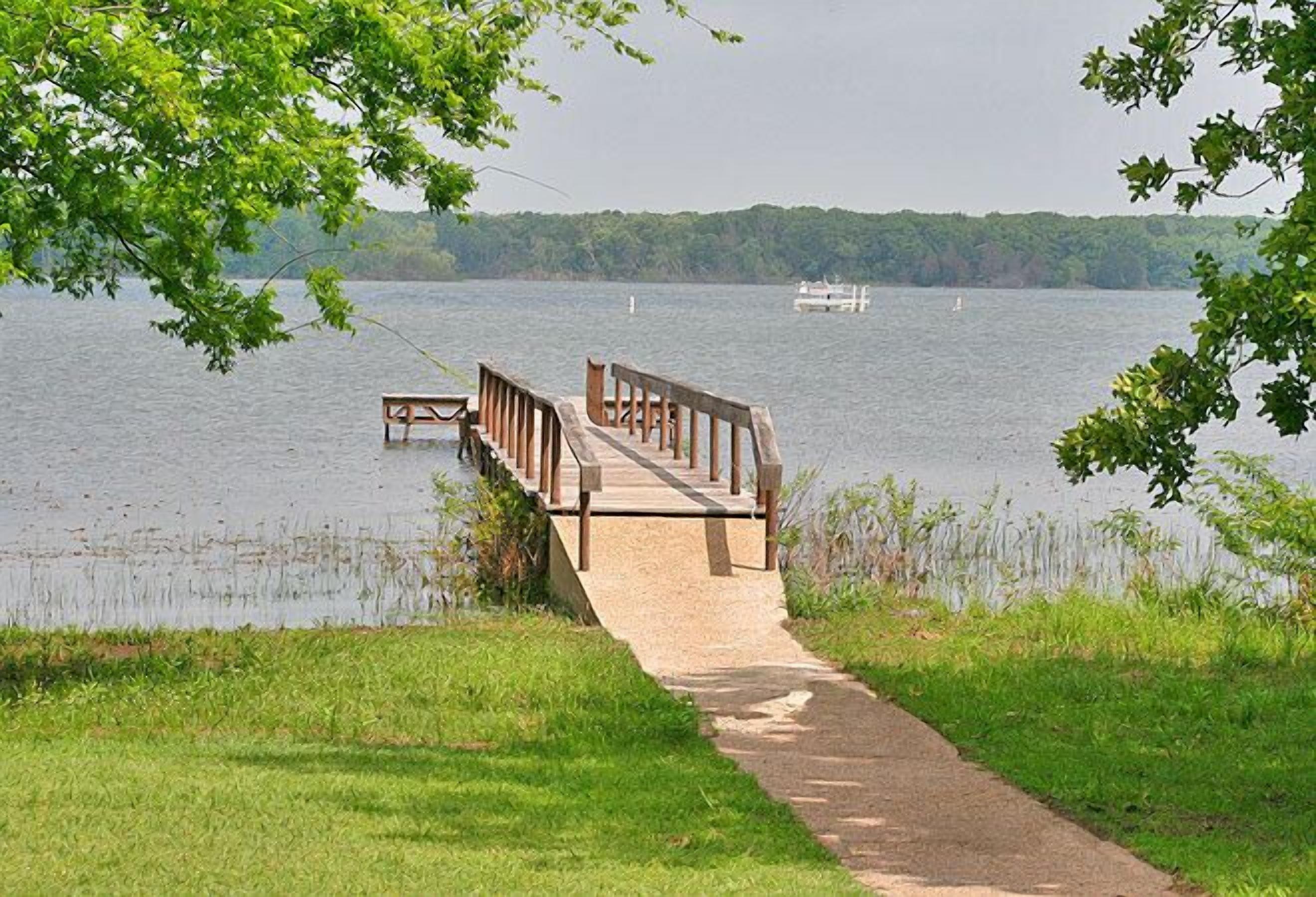 A wooden pier extending into a lake with a boat docked at the end.