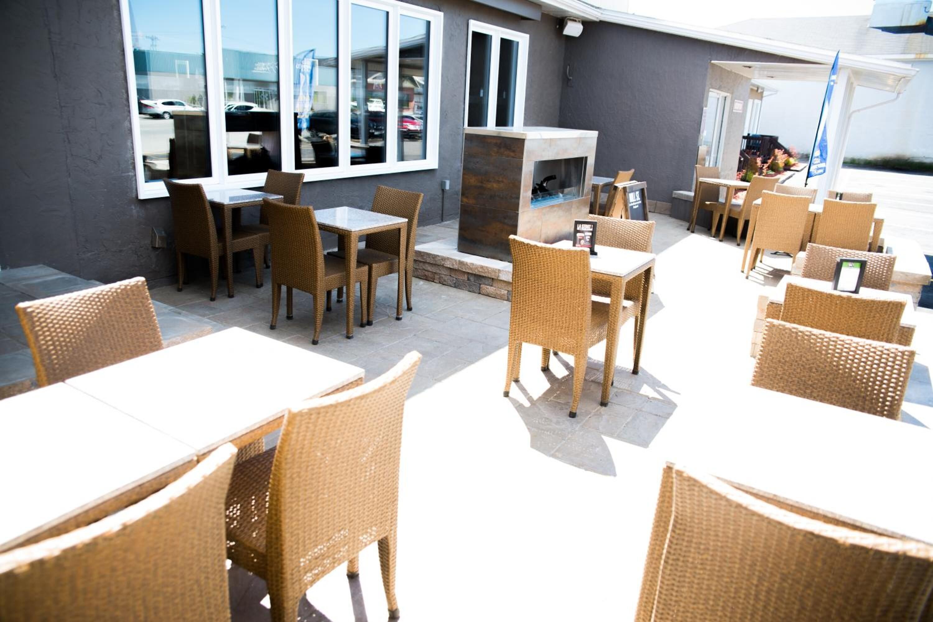 An outdoor dining area with wicker furniture and a stone fireplace.