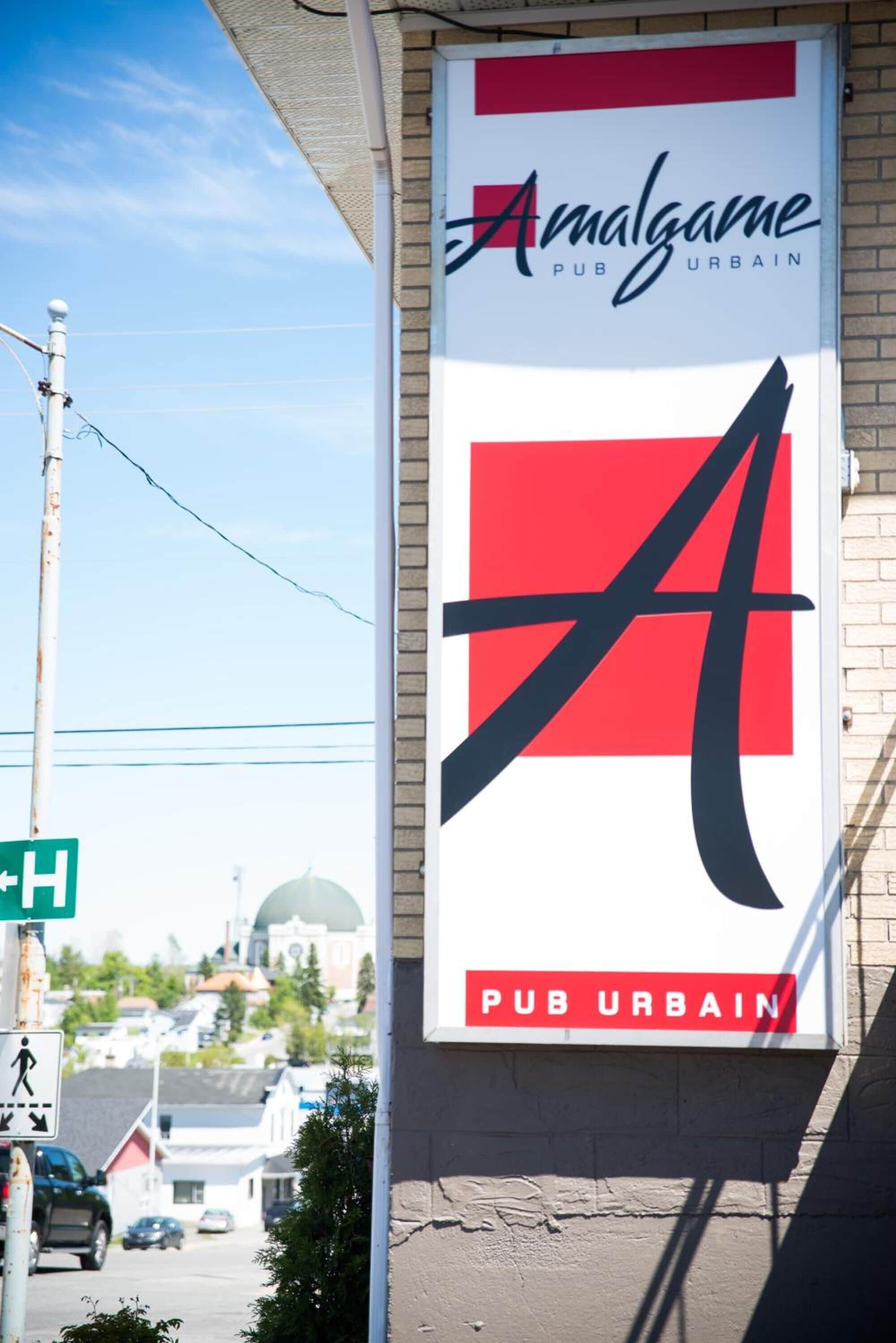 Un edificio con un letrero que dice 'Amalgame Pub Urbain', mostrando un logotipo estilizado de la letra 'A'.