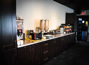 Efficient kitchen area with a commercial coffee machine, food processor, and kitchen utensils.