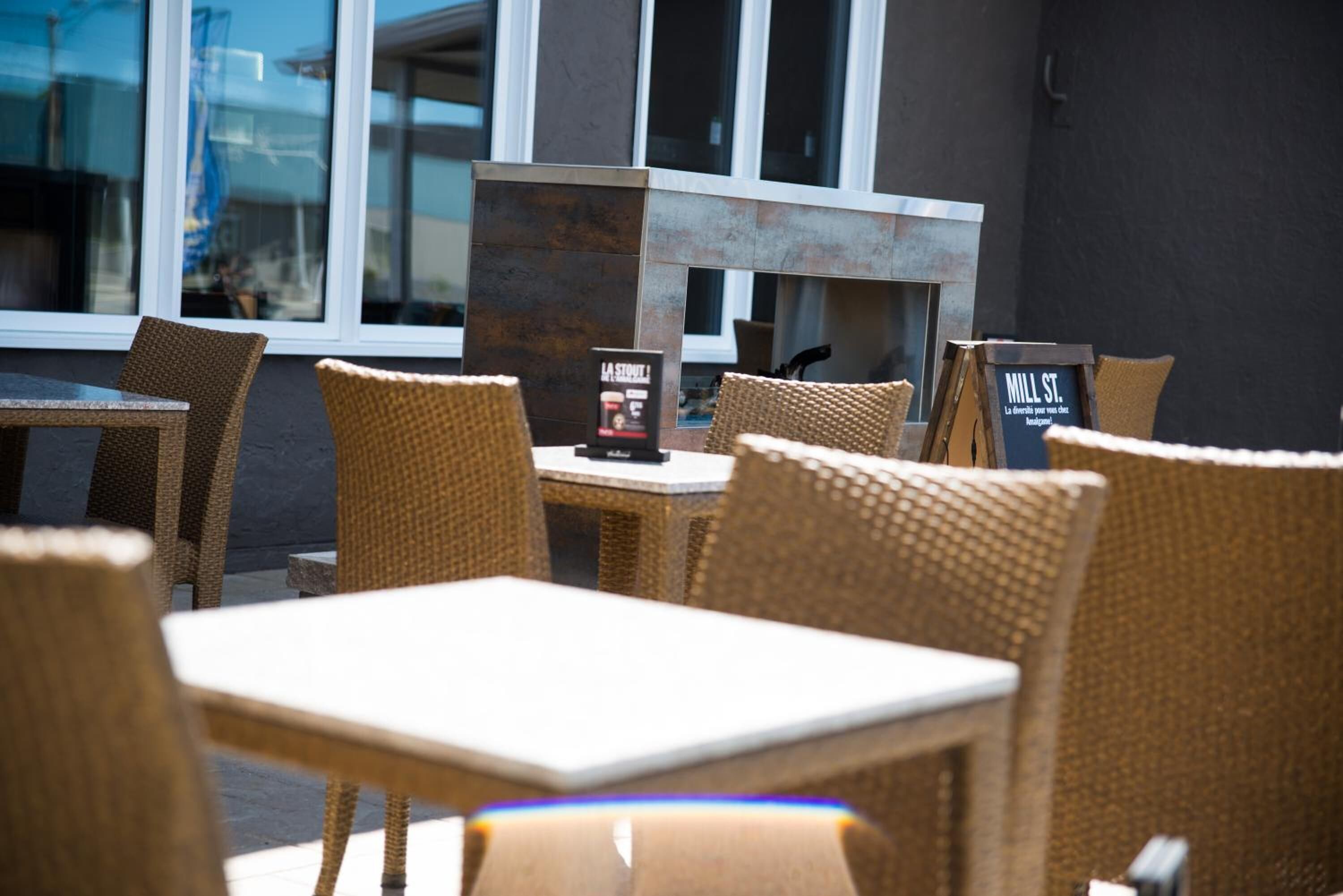 An outdoor seating area with wicker chairs and tables, a sign for 'La Société', and a 'Mill St.' sign.