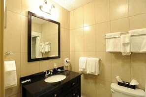 A bathroom with a black vanity, round sink, and mirror above, featuring a toilet and towel rack.