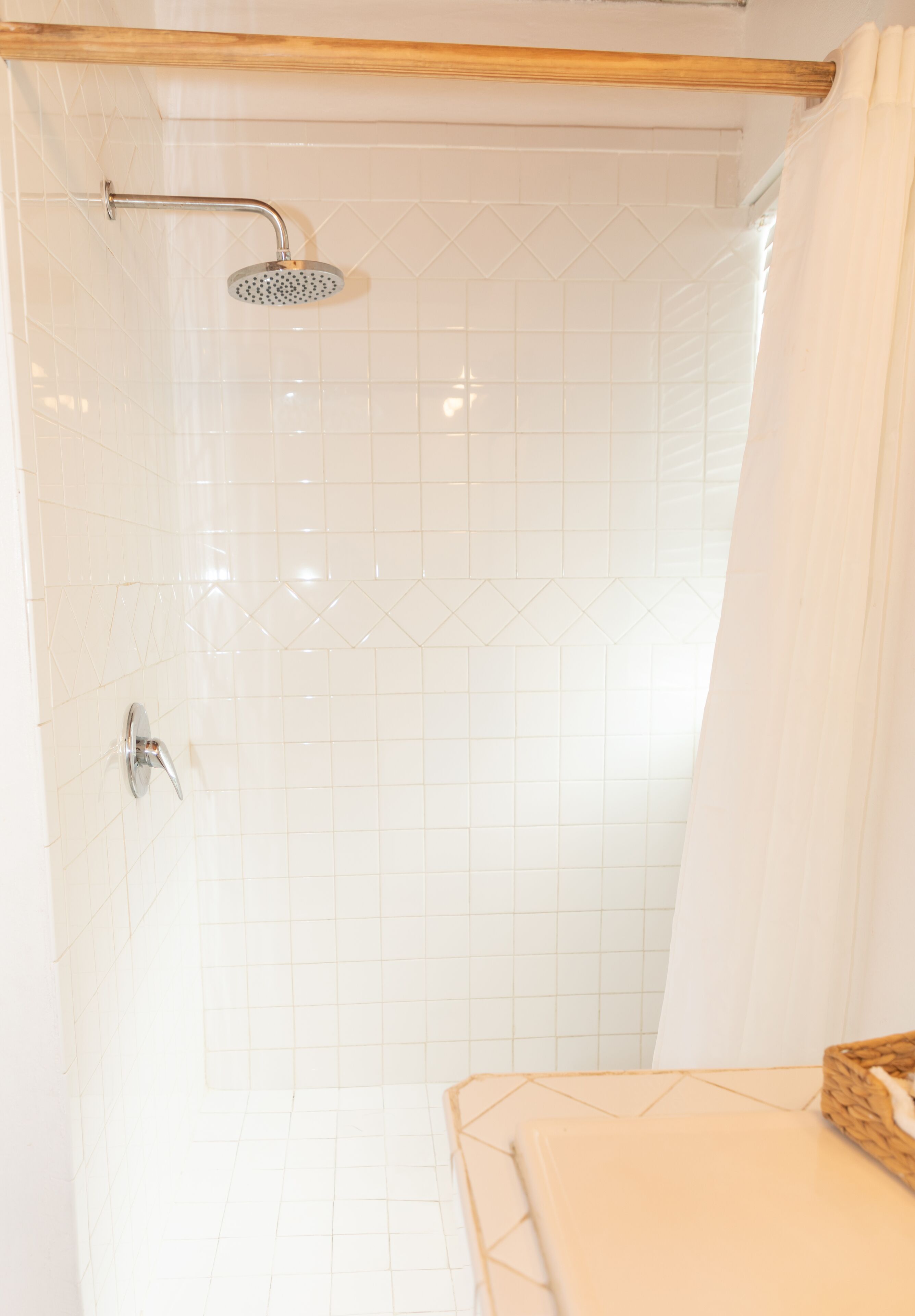 A shower with a handheld showerhead and a wall-mounted faucet.