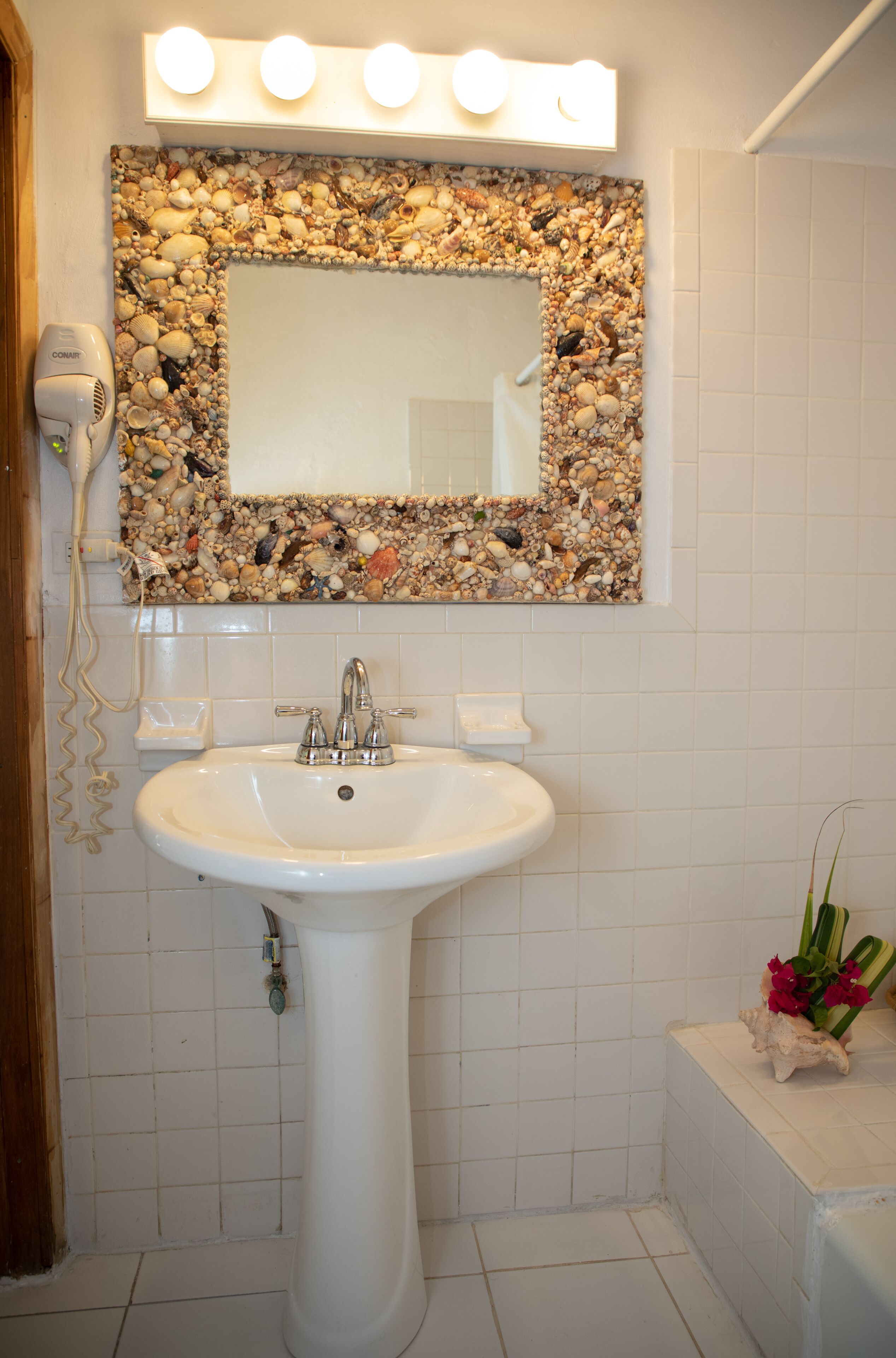 Ein Badezimmer mit Waschbecken, Spiegel und Beleuchtung darüber.