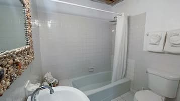 Un baño con bañera, inodoro, lavamanos y un espejo con marco decorativo.