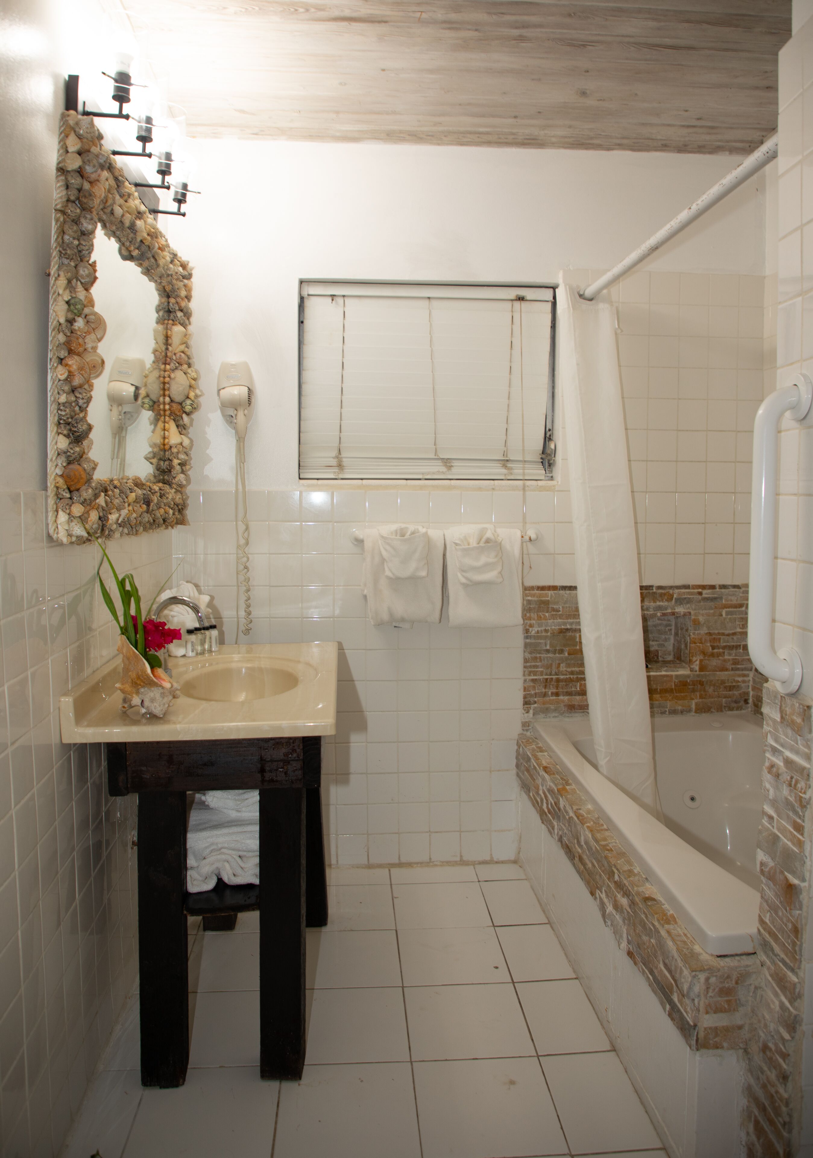 A bathroom with a sink, mirror, and shower.