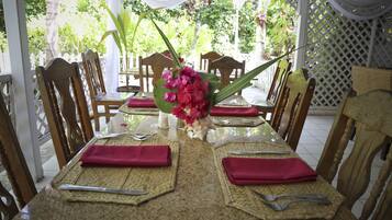 A dining table set with red napkins, cutlery, and a centerpiece of pink flowers.