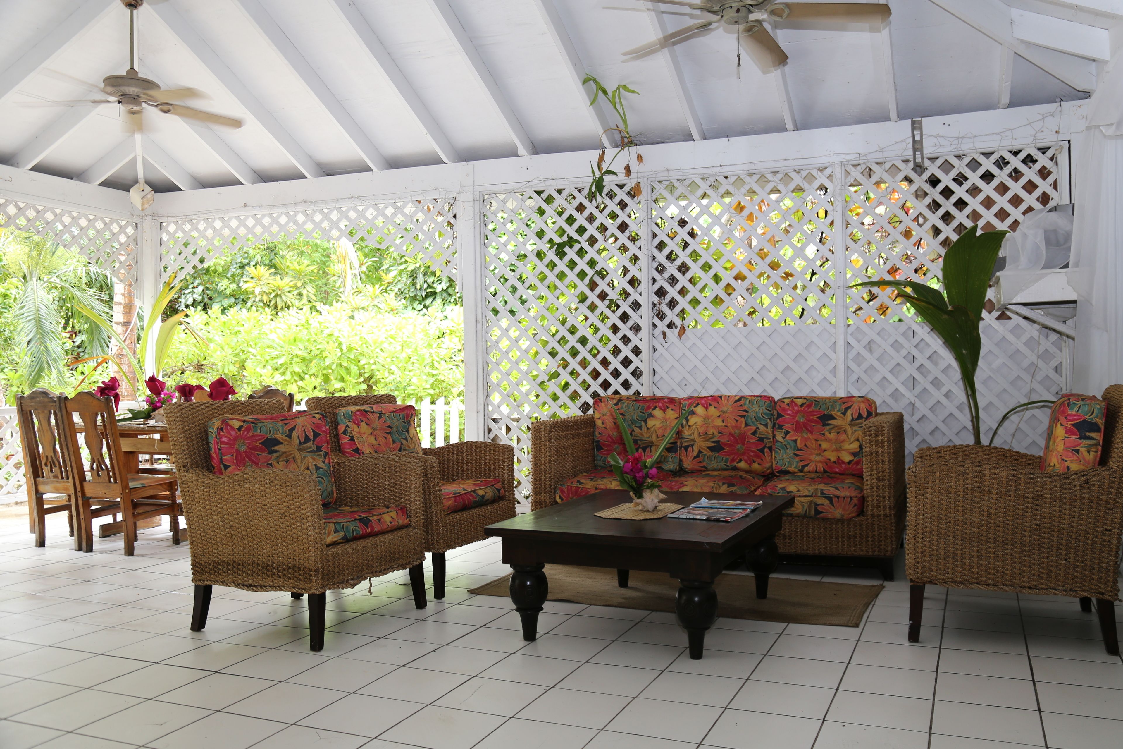 A covered patio area with wicker furniture, a ceiling fan, and a lattice wall.