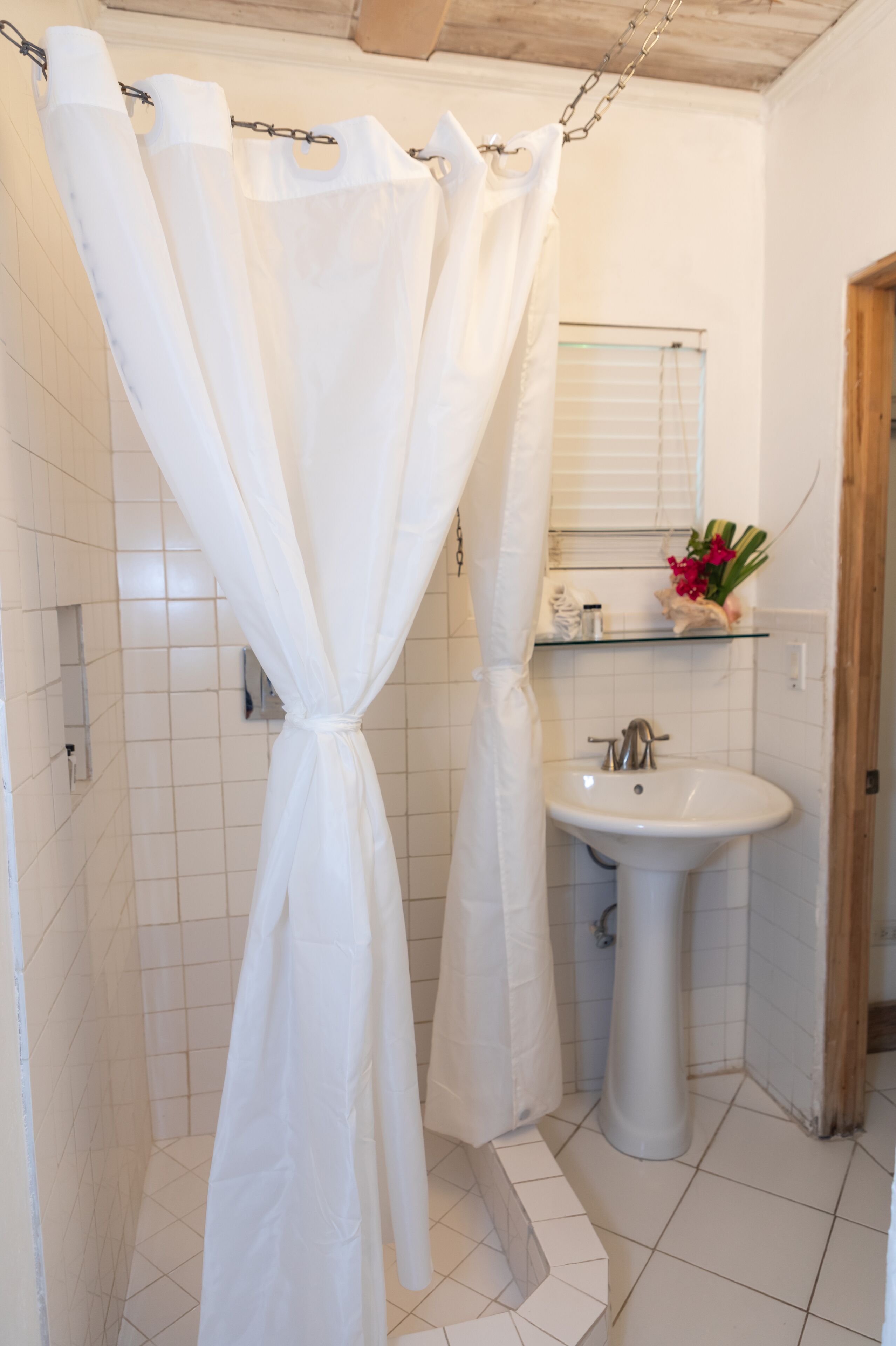 A bathroom with a shower curtain tied in a bow, a sink, and a mirror above it.