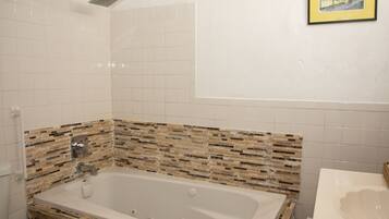A bathroom with a large bathtub, a shower, and a sink.