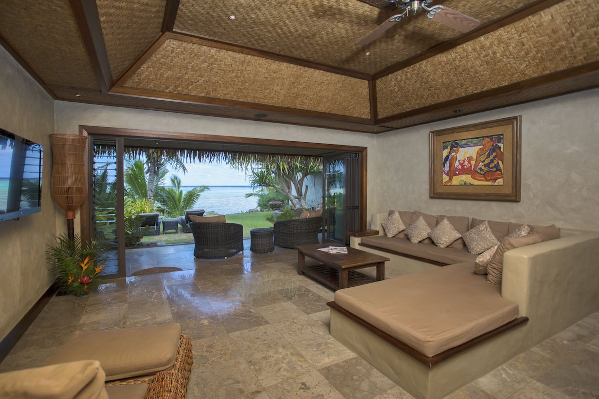 A spacious living area with a large sofa, a coffee table, and a view of the ocean through large glass doors.