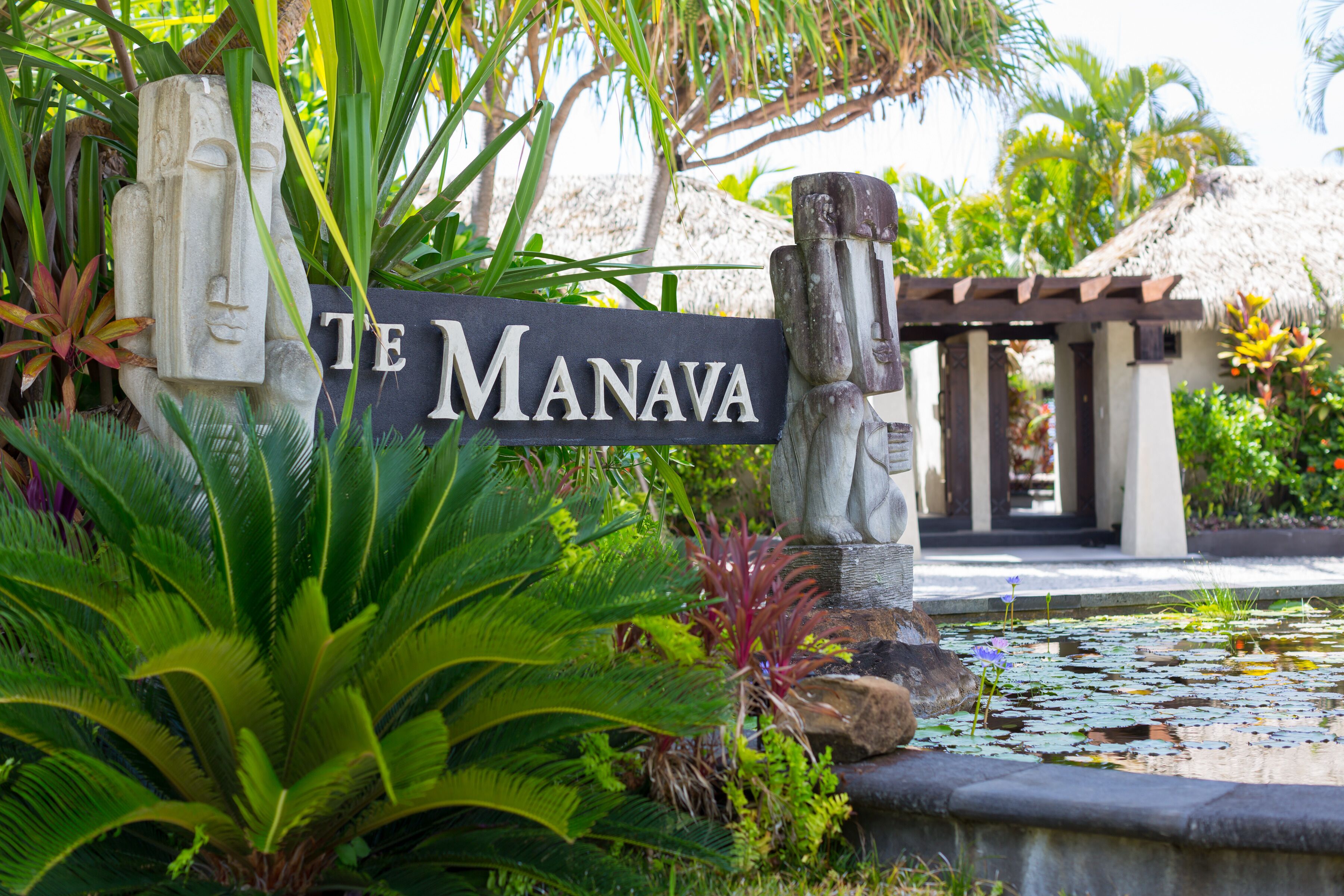 A sign reading "TE MANAVA" with tropical plants and a water feature in the foreground.