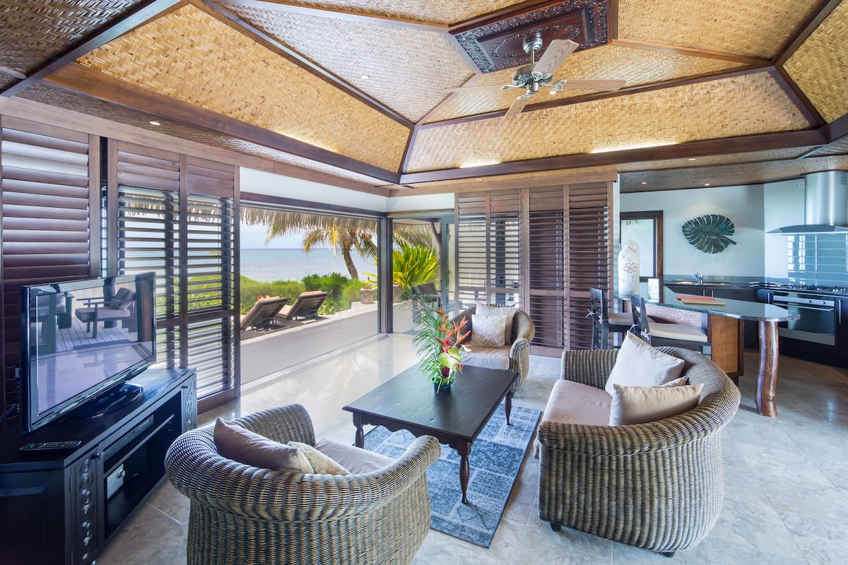 A spacious living area with a large TV, comfortable seating, and a view of the ocean.