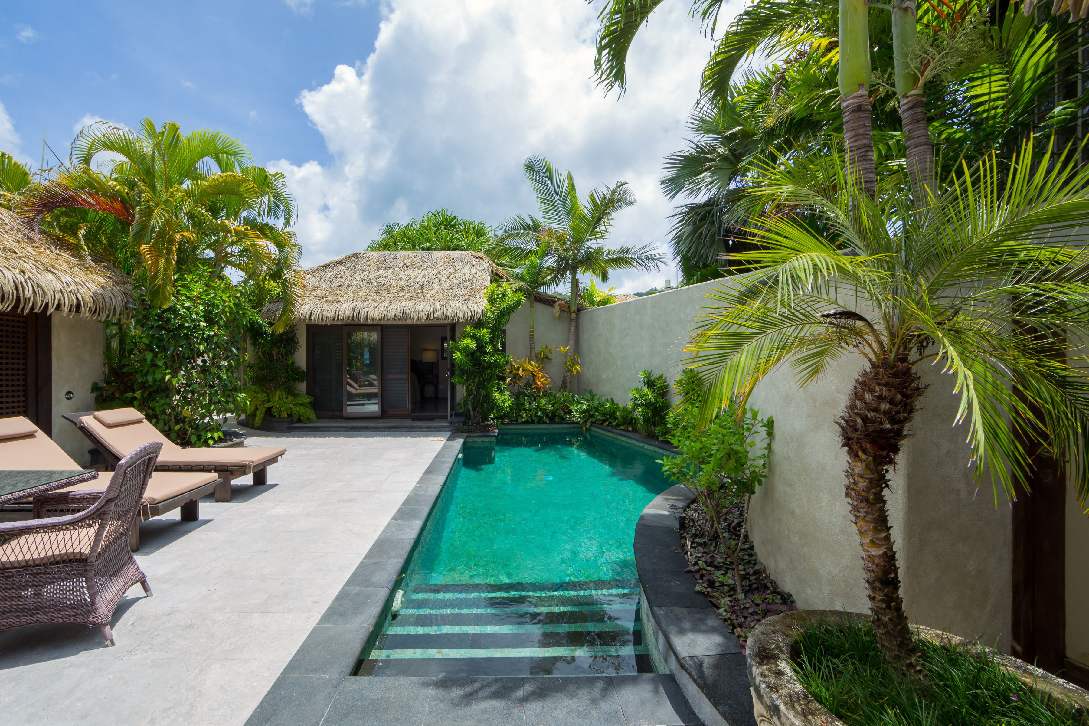 A swimming pool with lounge chairs and a thatched-roof structure.