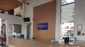 A hotel reception area with a counter, a sign reading "State Inn", and a view of the street outside.