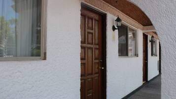 A corridor with a wooden door and a window with a curtain.