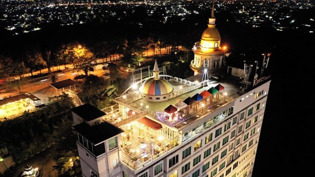 A high-rise hotel with a large, illuminated dome and multiple colorful umbrellas on the rooftop. - King's Hotel Nagoya Batam (Batam)
