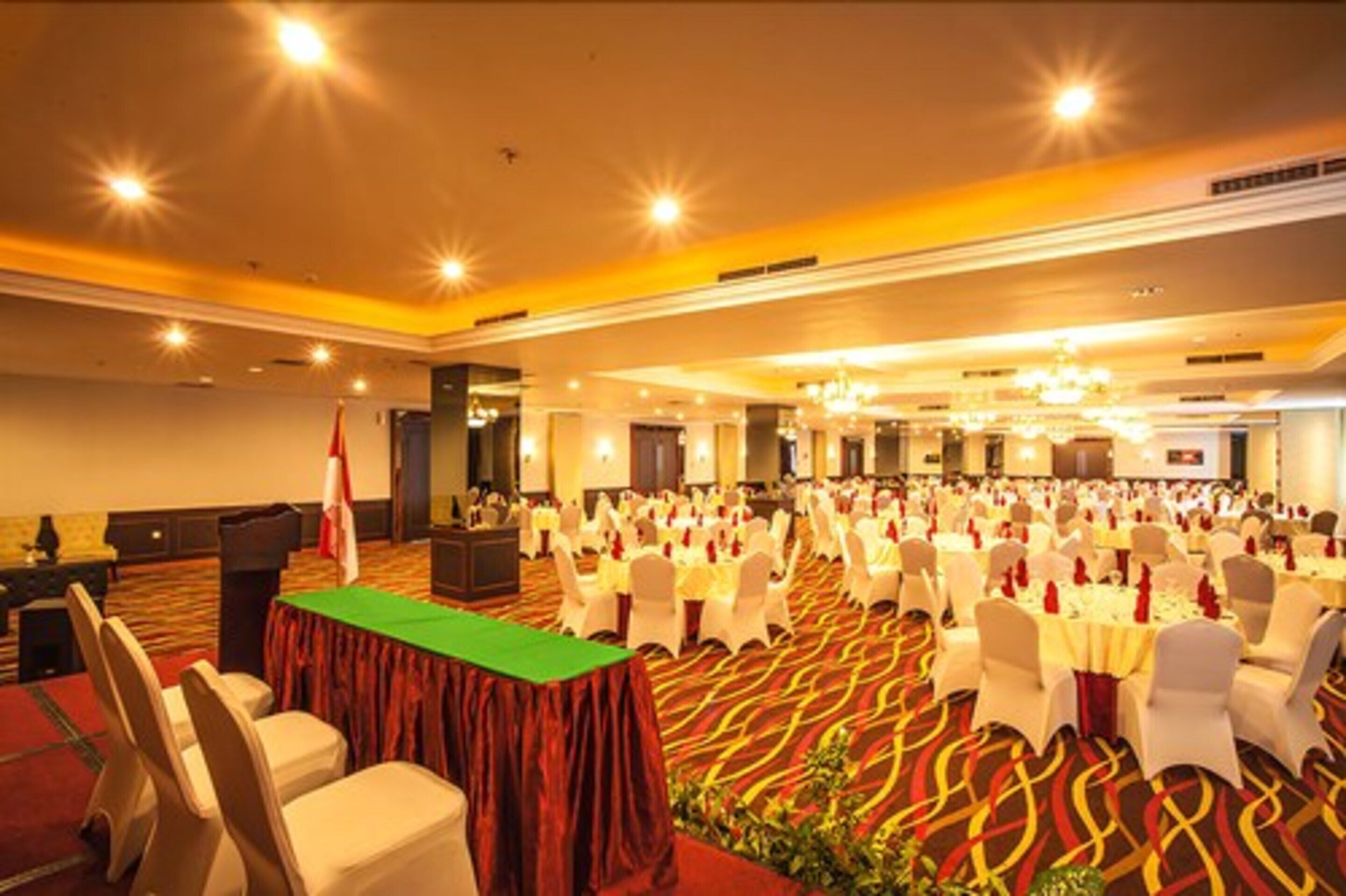 A banquet hall with rows of round tables, white chairs, and a red carpeted floor.