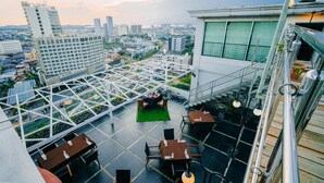 A rooftop terrace with tables and chairs, a glass ceiling structure, and a view of the cityscape. - King's Hotel Nagoya Batam (Batam)