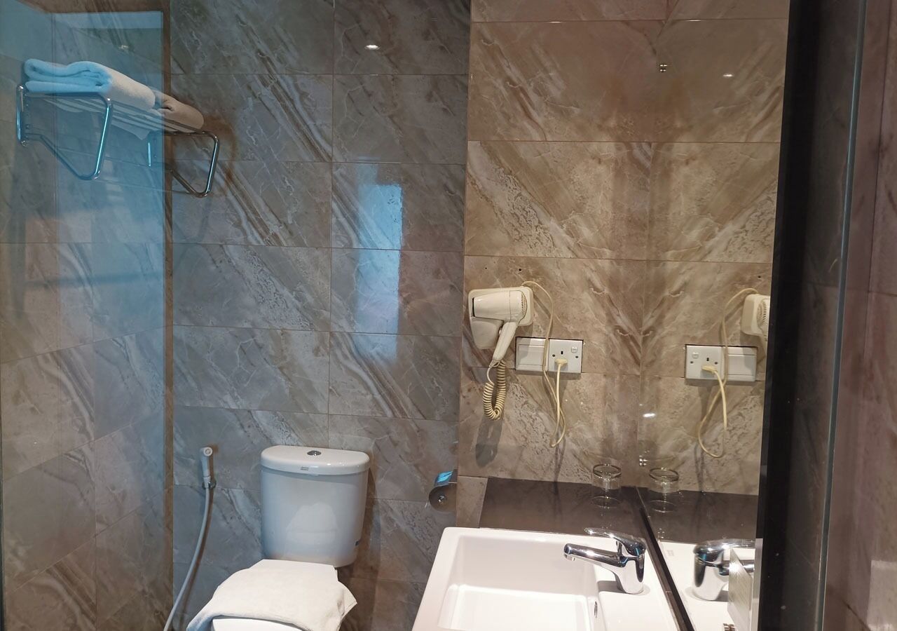 Une salle de bain équipée de toilettes, d’un lavabo, d’un sèche-cheveux et d’un porte-serviettes.