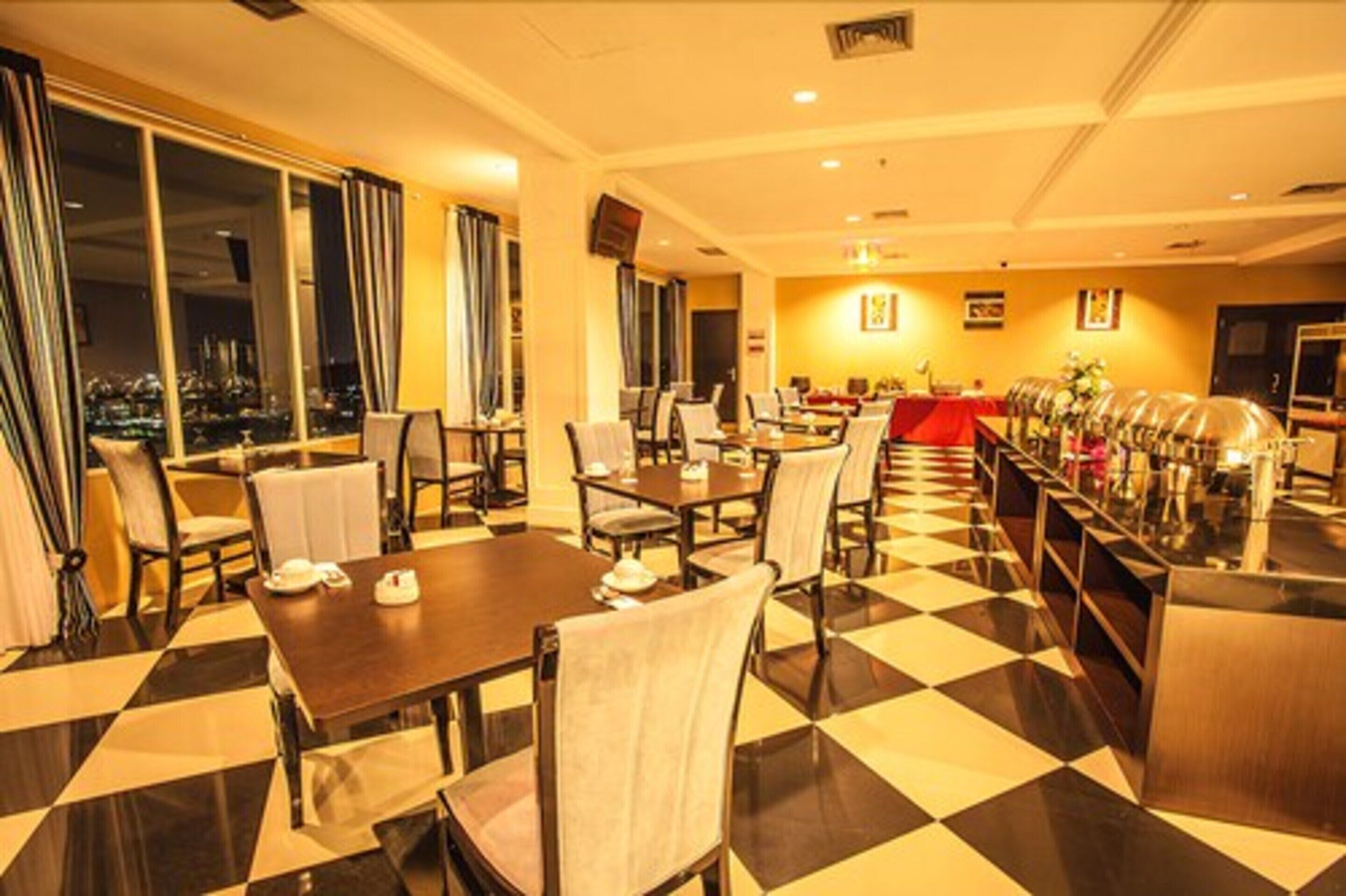 A hotel dining area with checkered flooring, multiple tables, chairs, and a buffet setup.