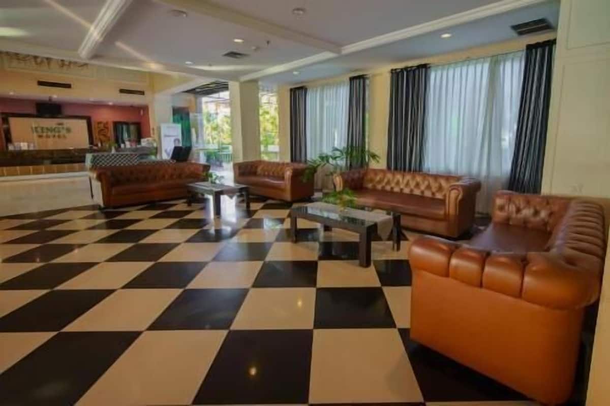 A hotel lobby with checkered flooring, leather sofas, and a coffee table.