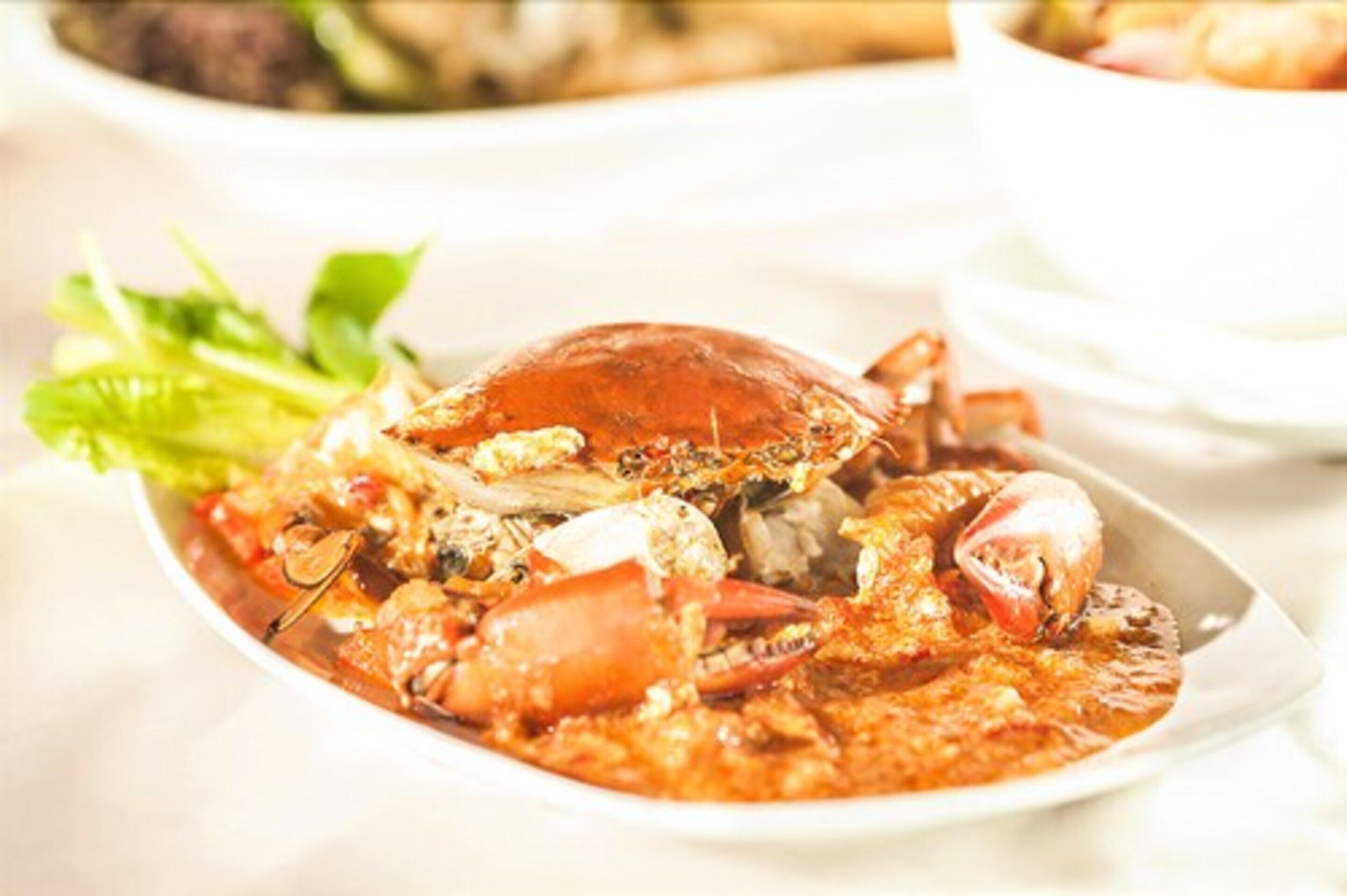 A seafood dish with a crab on a white plate, accompanied by a side of lettuce.