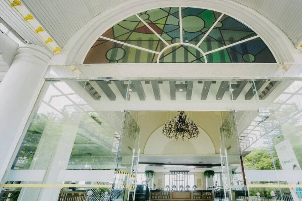 A spacious atrium with a high ceiling, large glass windows, and a central chandelier.