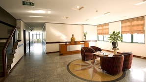 Un hall de hotel con mostrador de recepción, zona de estar y señal de salida.