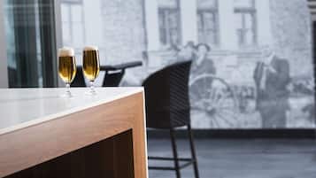 A modern interior with a wooden table and two glasses of wine, a bench, and a mural of a building with the name "BELMONT".