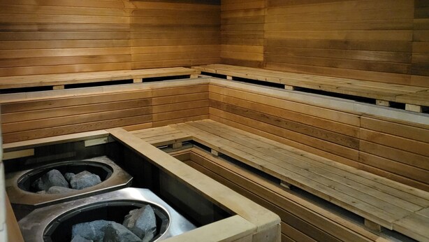 A sauna with wooden benches and two stone basins. - Days Inn & Suites by Wyndham Fort Saskatchewan (Fort Saskatchewan)