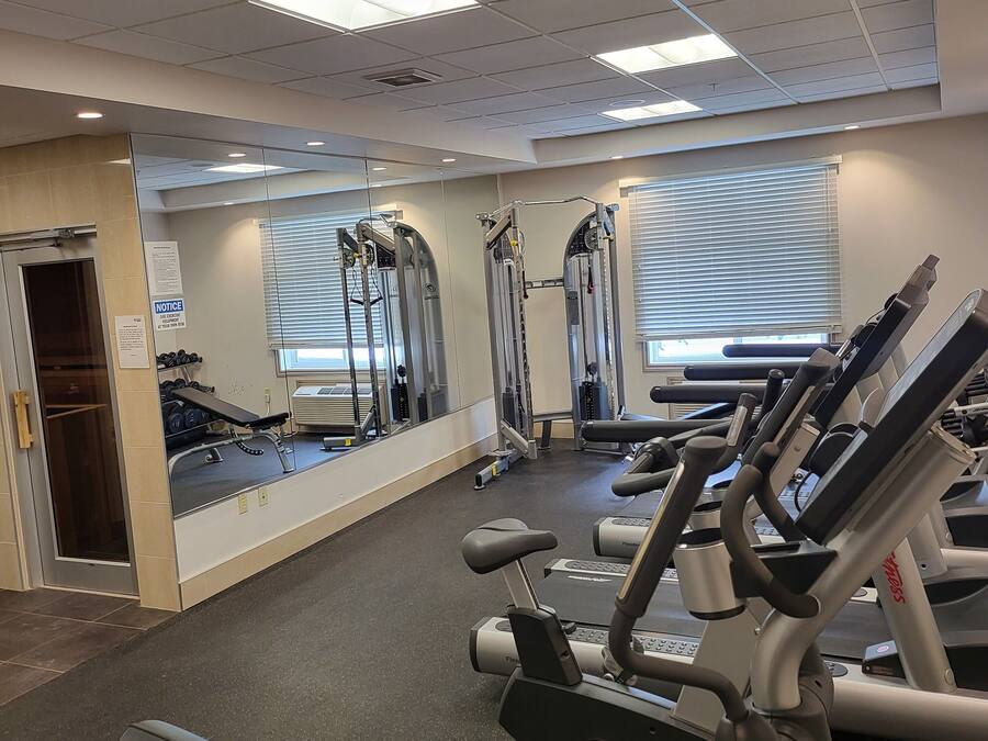 Un gimnasio con diversos equipos de ejercicio, incluyendo cintas de correr y máquinas de pesas.