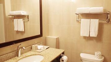 Une salle de bain équipée d’un lavabo, d’un miroir, d’un porte-serviettes, de toilettes et d’un support à papier toilette.