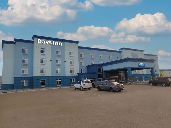 A Days Inn hotel with a blue and white exterior, multiple parking spaces, and a clear sky with clouds.