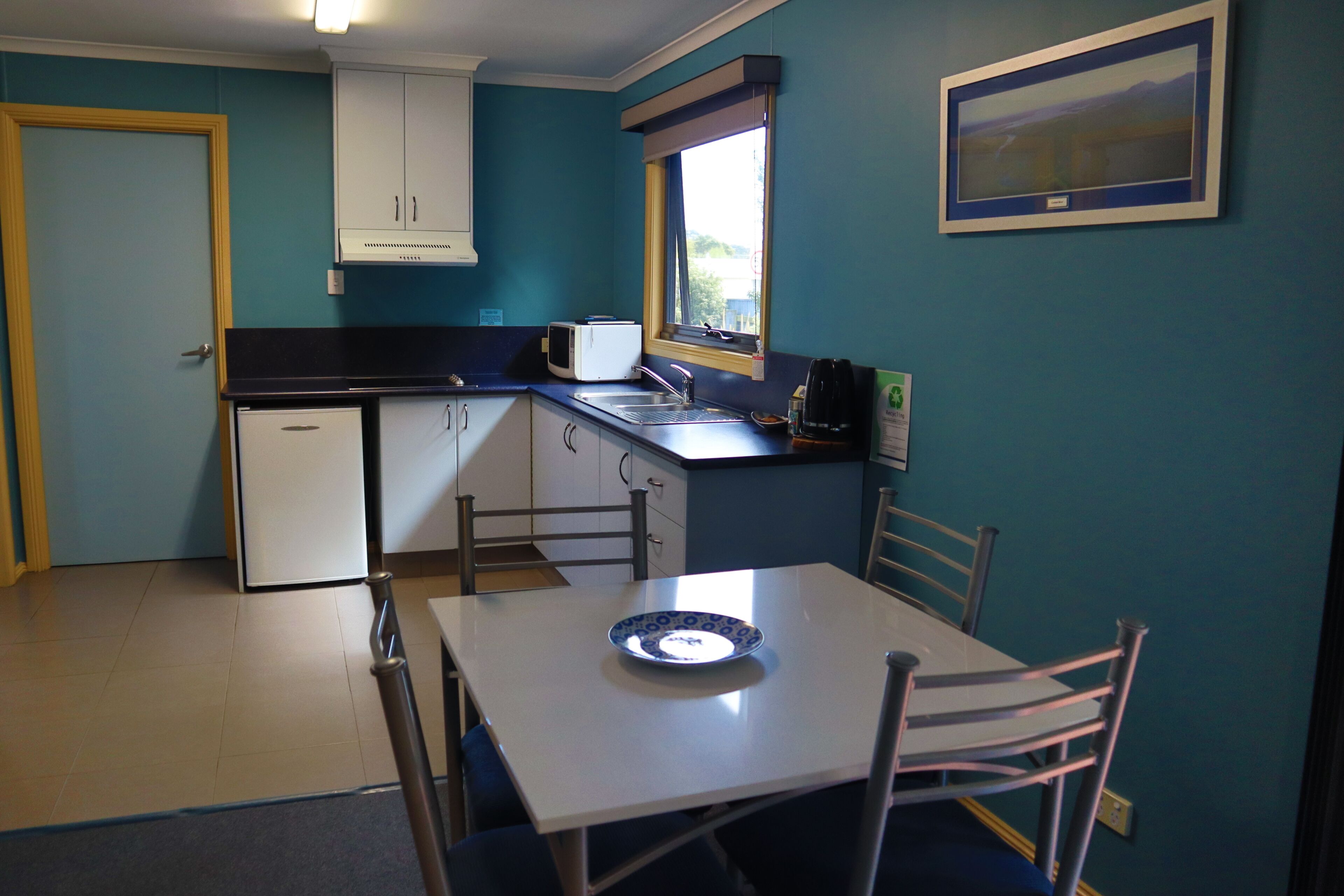 A compact kitchen with a microwave, sink, and window.
