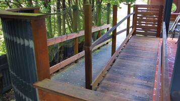 A wooden deck with a metal railing, surrounded by trees.