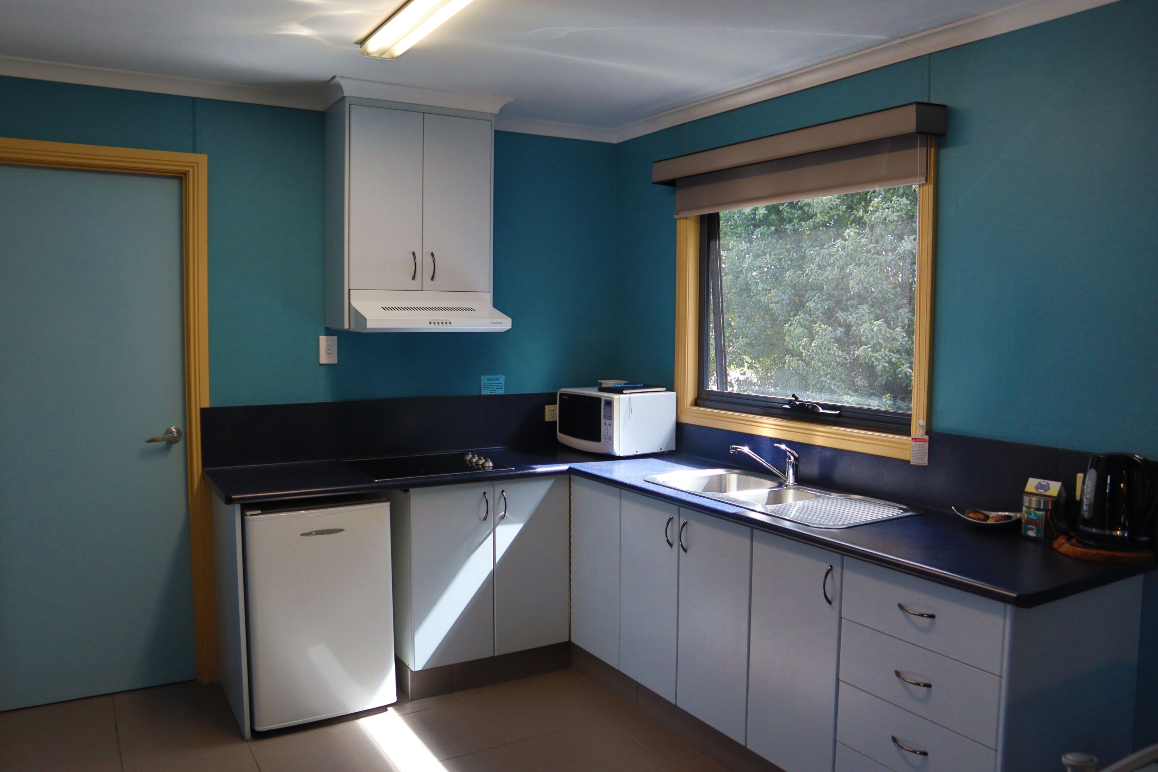 A compact kitchen with a microwave, sink, and cabinets.
