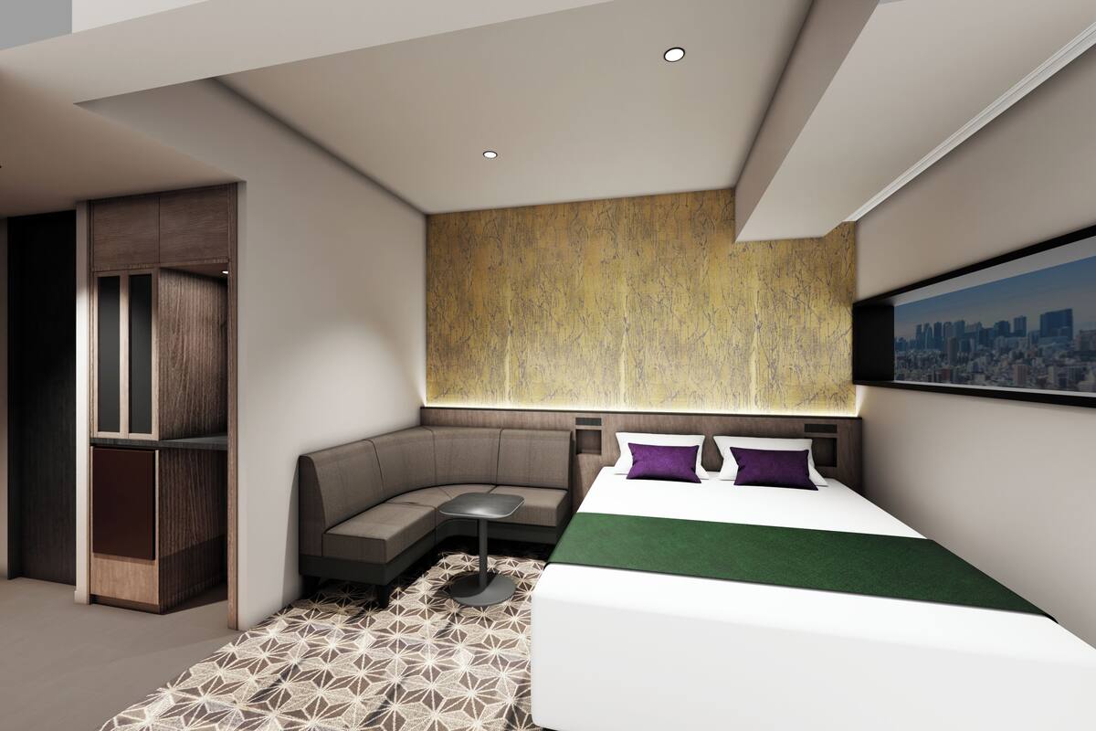 A modern hotel room with a bed, a seating area, a built-in wardrobe, and a cityscape view.